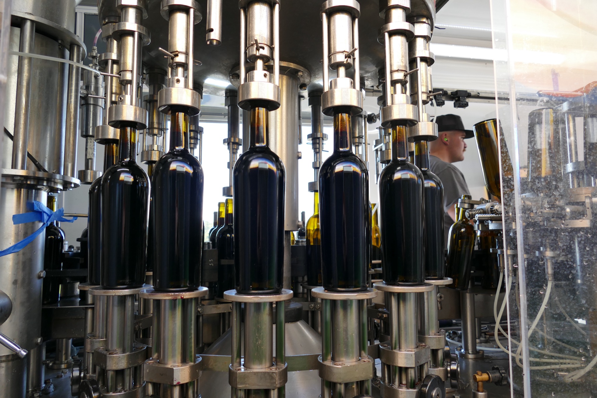 Wine filling unlabeled bottles on the rotary filler inside the mobile bottling line
