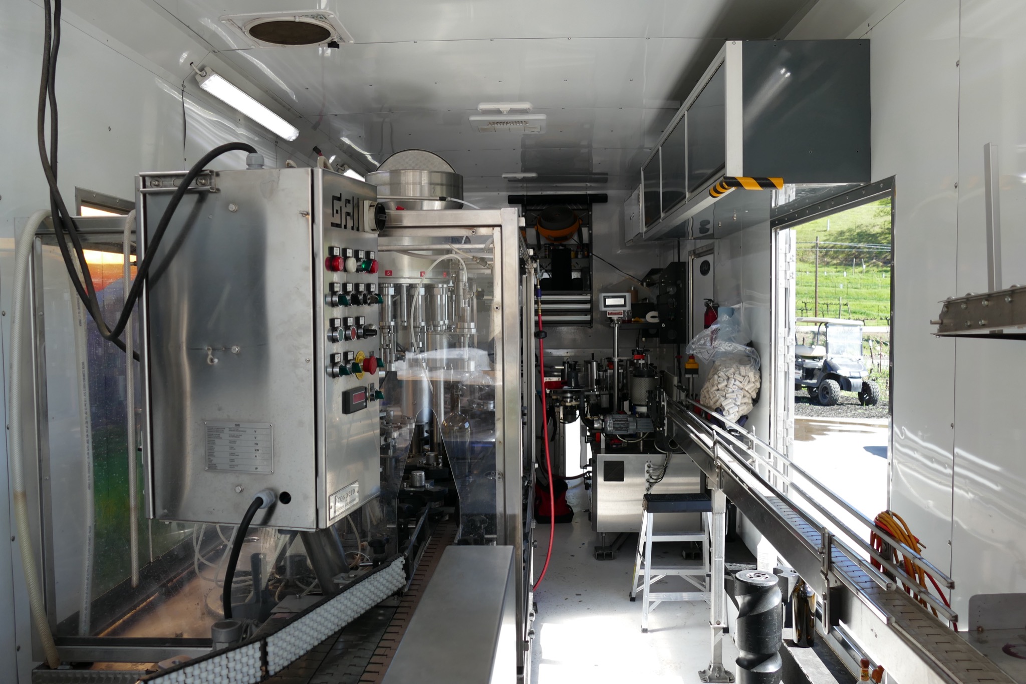 Inside the mobile bottling truck, with the filling line and labeler running the length of the trailer