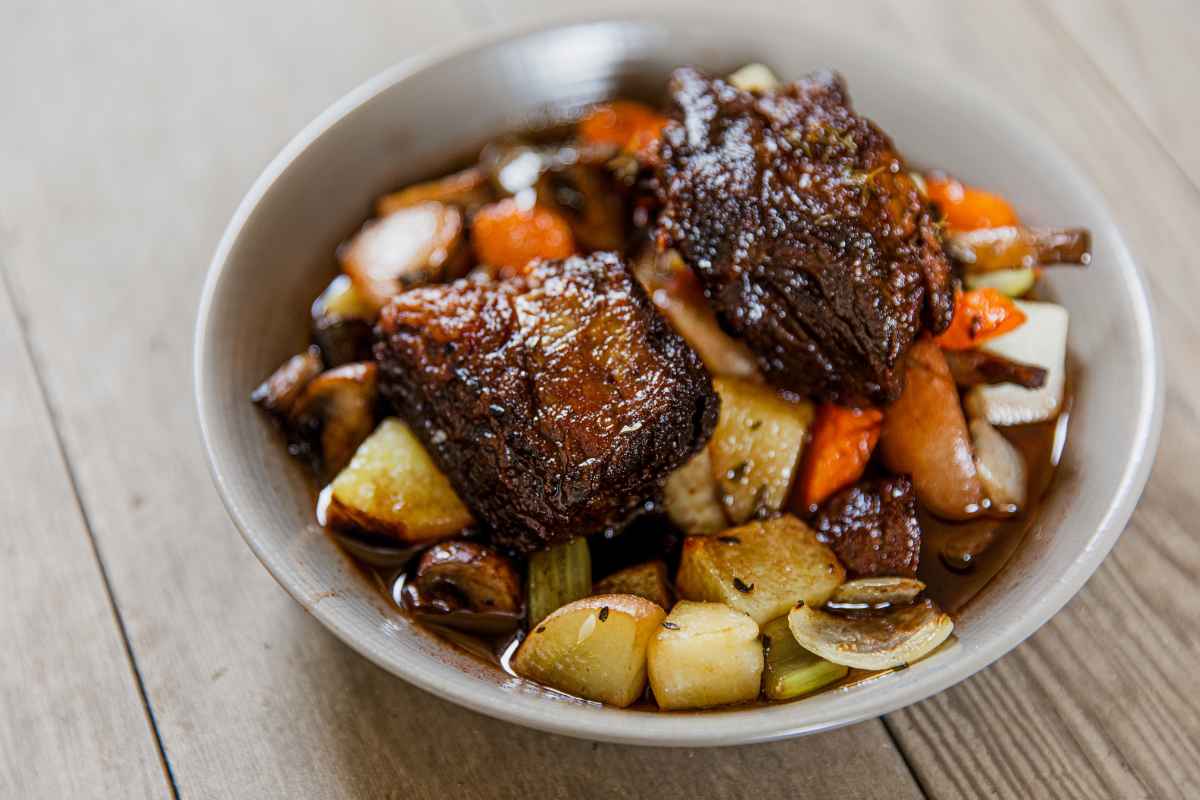 a bowl of short ribs with root vegetables